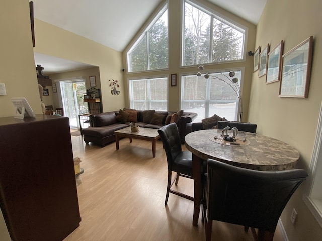 dining space featuring high vaulted ceiling and light hardwood / wood-style flooring