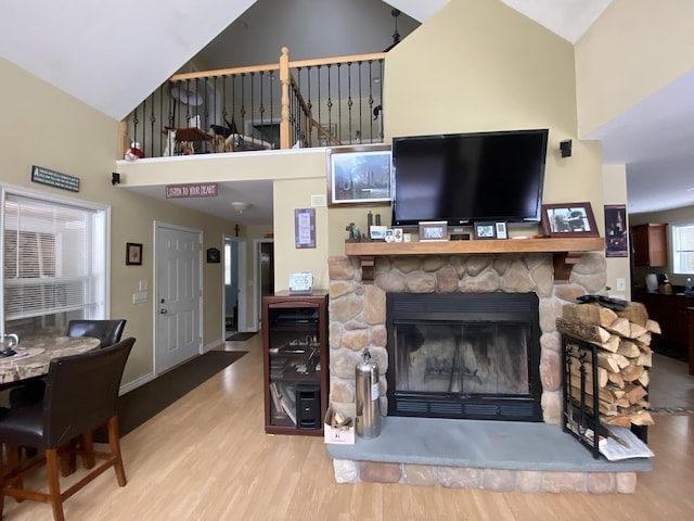 living room featuring lofted ceiling, hardwood / wood-style flooring, and a stone fireplace