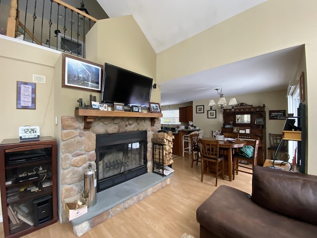 living room featuring lofted ceiling, a stone fireplace, and light hardwood / wood-style floors