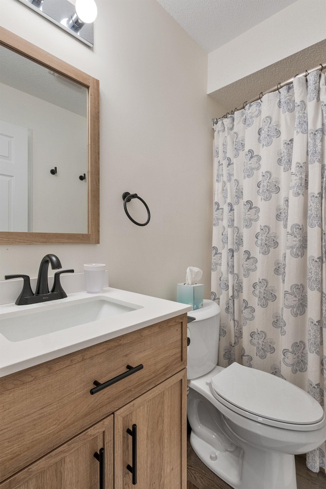 bathroom featuring vanity, toilet, and a textured ceiling