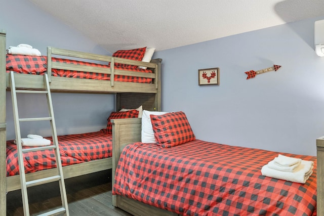 bedroom featuring lofted ceiling, hardwood / wood-style flooring, and a textured ceiling