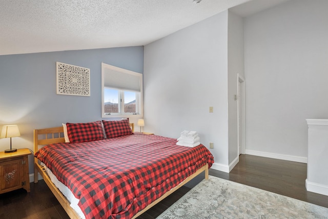 bedroom with lofted ceiling, dark wood-type flooring, and a textured ceiling