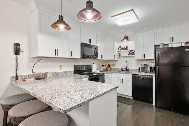 kitchen with white cabinets, a kitchen breakfast bar, kitchen peninsula, and black appliances