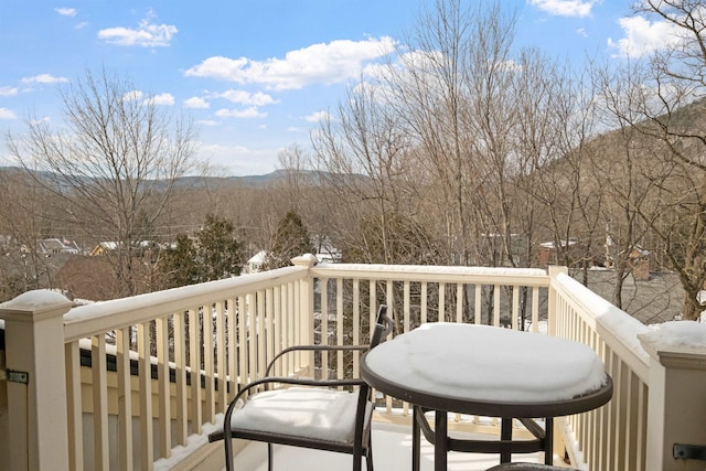 snow covered back of property with a deck with mountain view