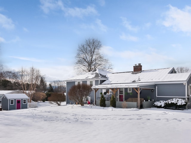 snow covered house with a shed and a porch