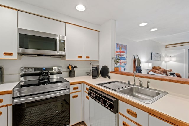 kitchen with white cabinetry, sink, stainless steel appliances, and kitchen peninsula