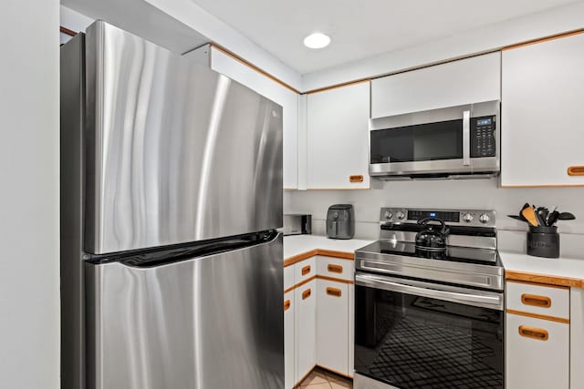 kitchen with light tile patterned flooring, white cabinets, and appliances with stainless steel finishes