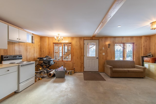 interior space with white cabinetry, wooden walls, a notable chandelier, white range with electric cooktop, and beam ceiling