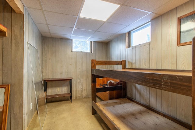 interior space featuring a paneled ceiling and wood walls