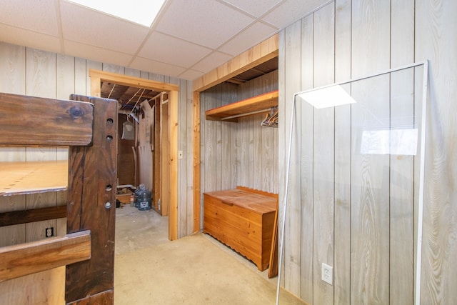 interior space featuring a drop ceiling, concrete floors, and wood walls