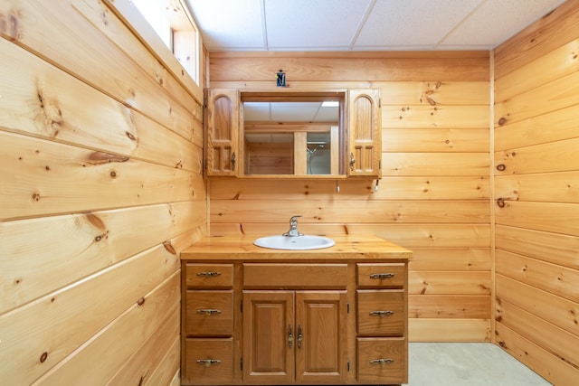 bathroom featuring vanity, wooden walls, and a drop ceiling