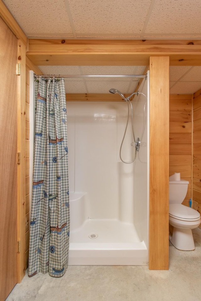 bathroom with a shower with curtain, a paneled ceiling, wooden walls, and toilet