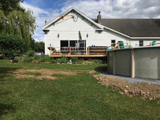 rear view of property featuring a lawn and a swimming pool side deck