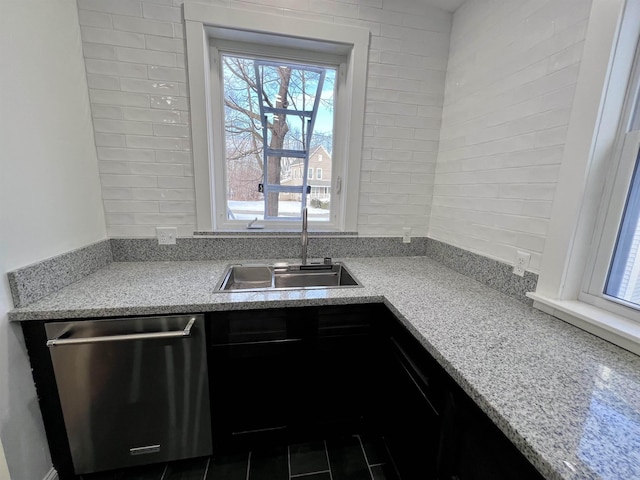 kitchen featuring light stone countertops, sink, and stainless steel dishwasher