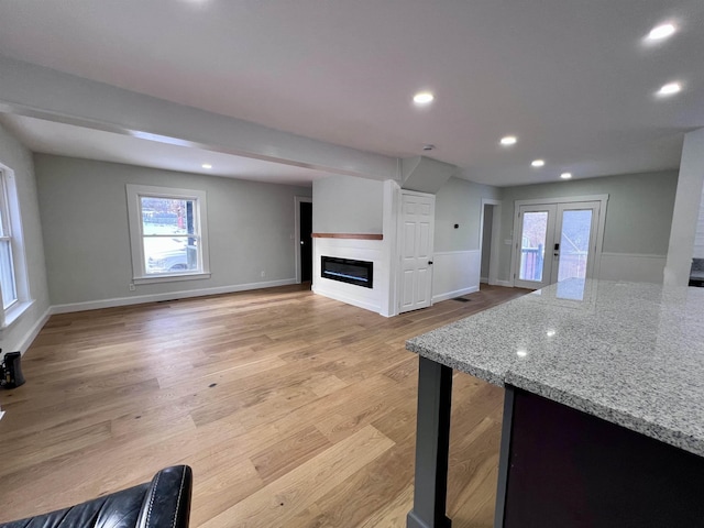 kitchen featuring light hardwood / wood-style flooring, light stone countertops, and french doors