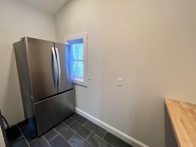 kitchen featuring stainless steel refrigerator and dark tile patterned flooring