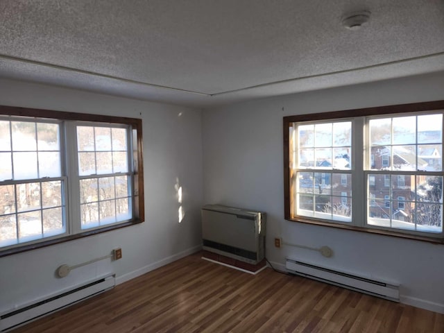 empty room featuring a baseboard radiator, a textured ceiling, a baseboard heating unit, and dark wood-style flooring