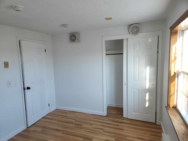 unfurnished bedroom featuring a closet, hardwood / wood-style floors, and a textured ceiling