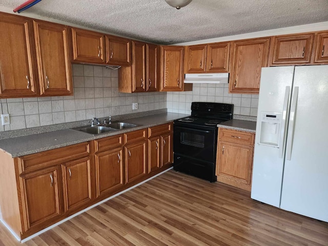 kitchen featuring under cabinet range hood, a sink, brown cabinets, white fridge with ice dispenser, and black electric range oven