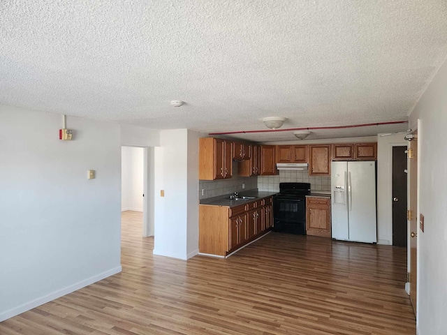 kitchen with sink, white fridge with ice dispenser, hardwood / wood-style flooring, black range with electric stovetop, and decorative backsplash