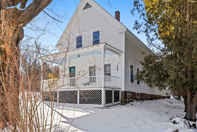 snow covered house featuring a porch