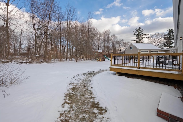 yard covered in snow with a wooden deck and a playground