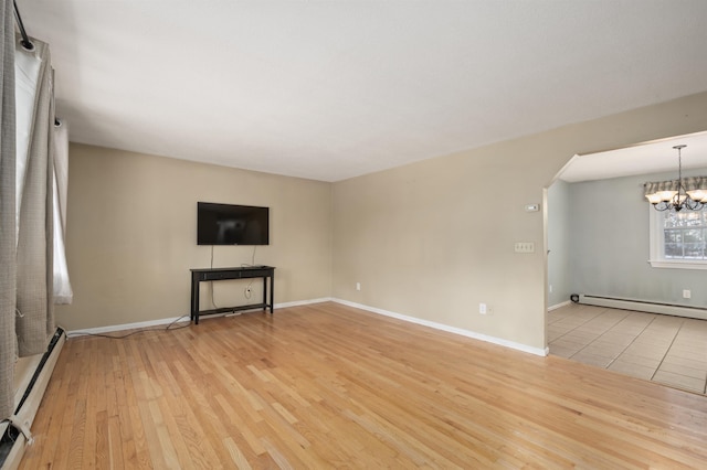 unfurnished living room with a baseboard radiator, a notable chandelier, and light wood-type flooring