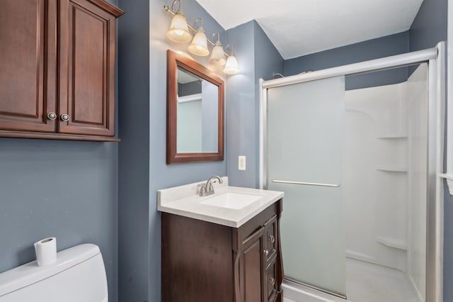 bathroom featuring vanity, a shower with door, and toilet