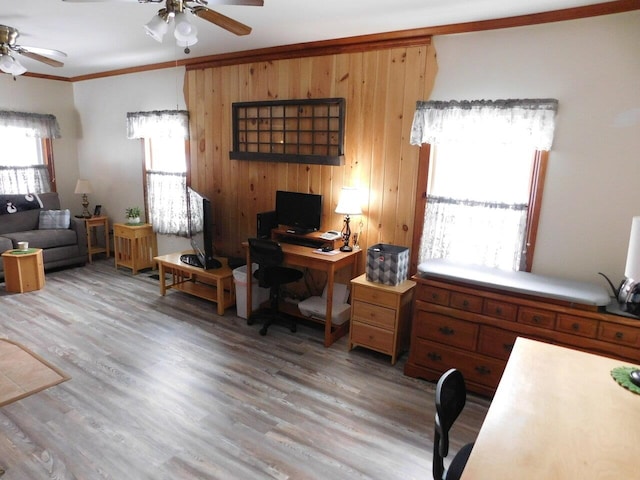 home office featuring wood-type flooring, ornamental molding, ceiling fan, and wood walls