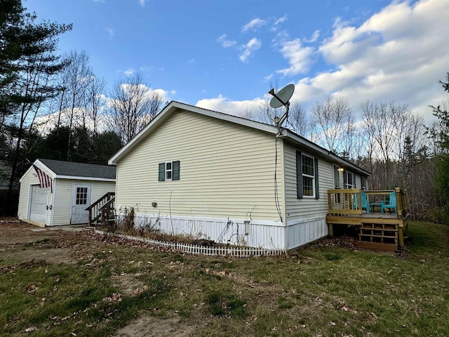 view of home's exterior featuring a garage, an outdoor structure, a deck, and a lawn