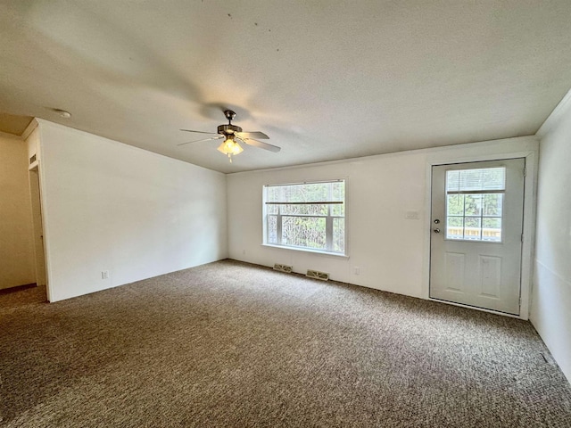 carpeted empty room with ceiling fan and a textured ceiling