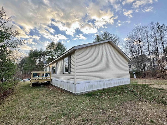 view of side of home with a wooden deck and a yard