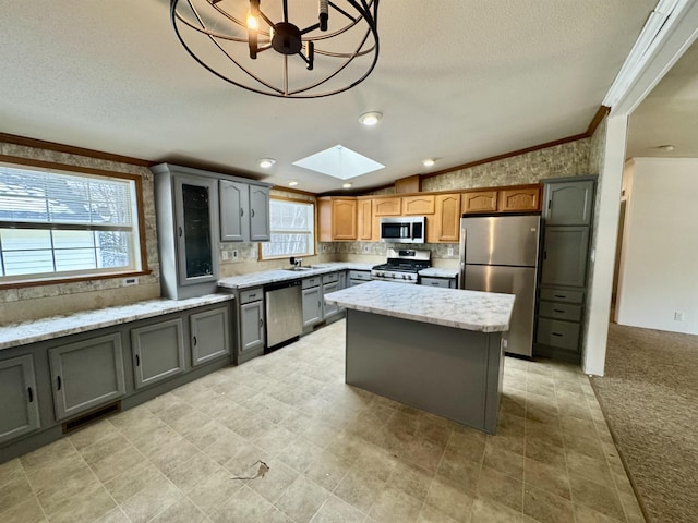 kitchen with light stone counters, stainless steel appliances, a kitchen island, and hanging light fixtures