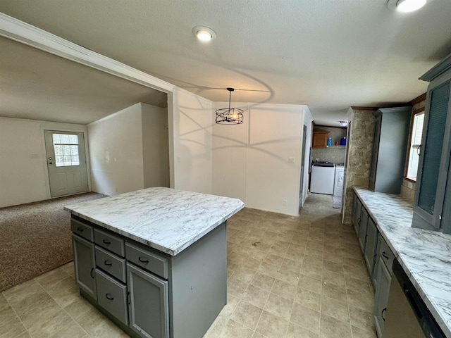 kitchen featuring gray cabinets, decorative light fixtures, separate washer and dryer, a center island, and light carpet