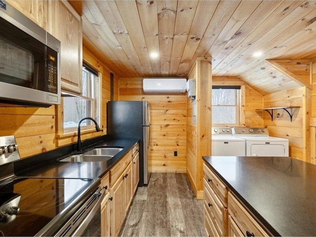 kitchen featuring sink, wood walls, washer and dryer, a wall unit AC, and stainless steel appliances