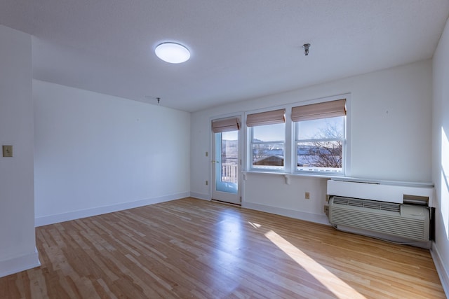 empty room with a wall mounted AC and light wood-type flooring