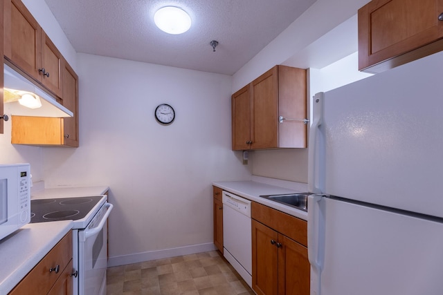 kitchen featuring sink, a textured ceiling, and white appliances