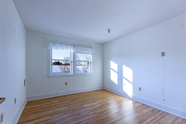 empty room with a textured ceiling and light wood-type flooring