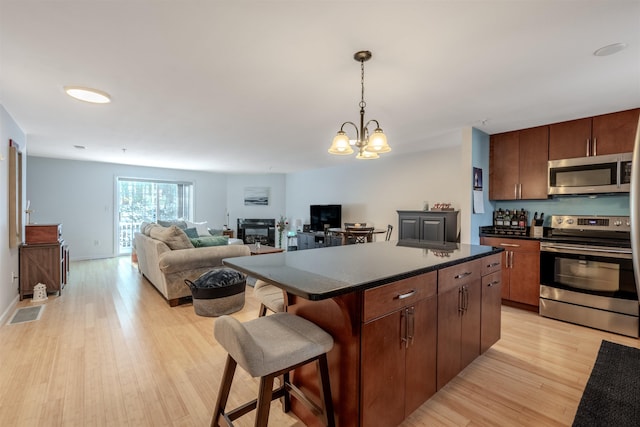 kitchen with a breakfast bar, appliances with stainless steel finishes, a center island, and light wood-type flooring