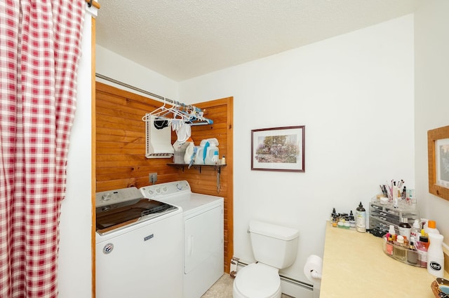 laundry area featuring washer and clothes dryer, a baseboard radiator, a textured ceiling, and wood walls