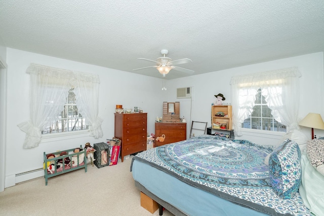 bedroom with ceiling fan, baseboard heating, a wall mounted AC, carpet, and a textured ceiling