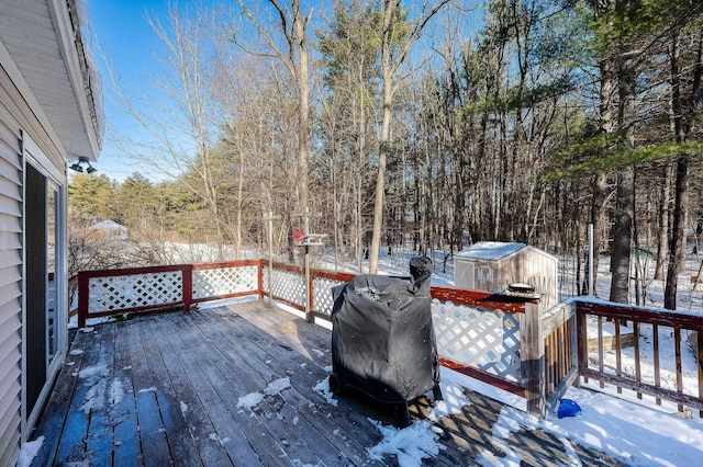 snow covered deck with a grill and a shed