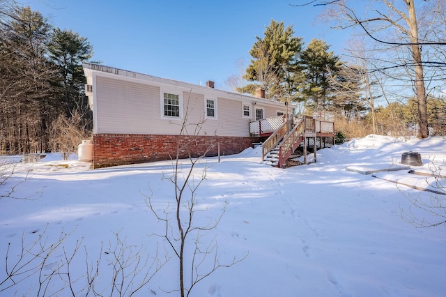 snow covered back of property featuring a wooden deck