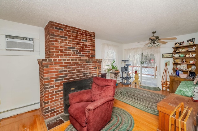 living area featuring a baseboard heating unit, a textured ceiling, a wall mounted AC, and hardwood / wood-style flooring