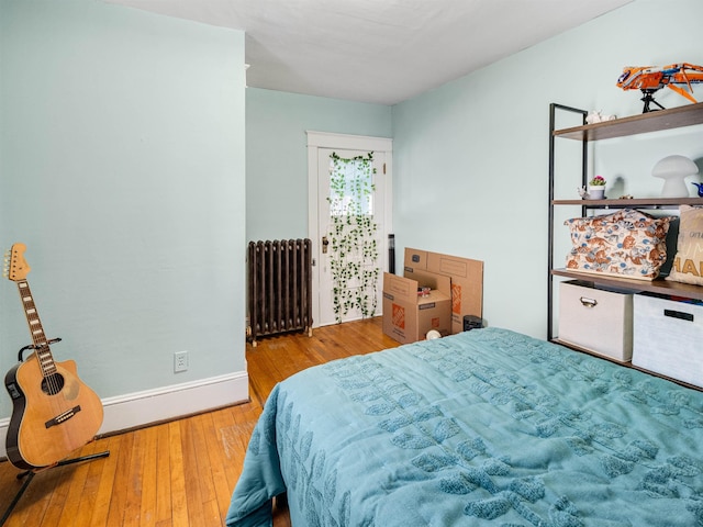 bedroom with radiator heating unit and light wood-type flooring