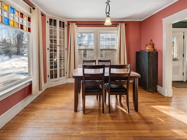 dining room with ornamental molding and light wood-type flooring