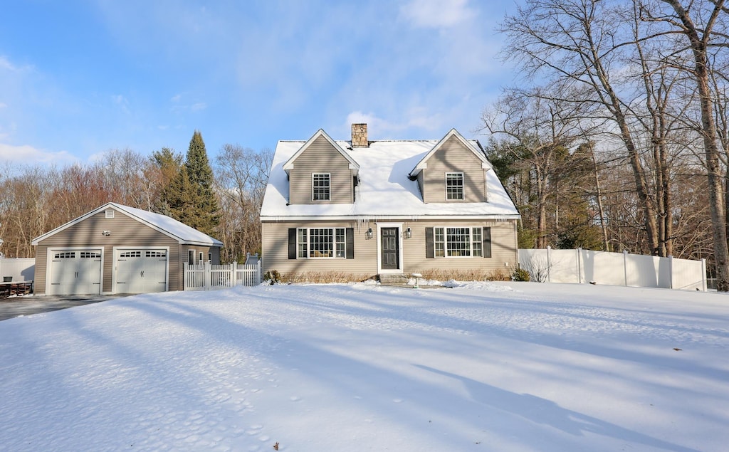 cape cod house featuring a garage and an outbuilding