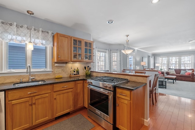 kitchen with pendant lighting, kitchen peninsula, sink, and stainless steel gas range oven