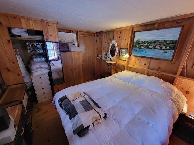 bedroom featuring wood-type flooring, wooden walls, and a closet