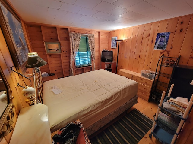 bedroom with light hardwood / wood-style floors and wood walls